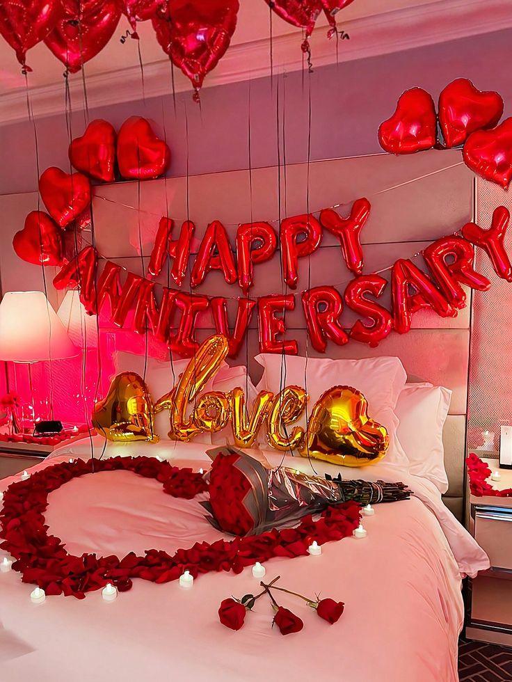 Romantic anniversary bedroom decoration with red heart balloons, Happy Anniversary foil letters and rose petal heart