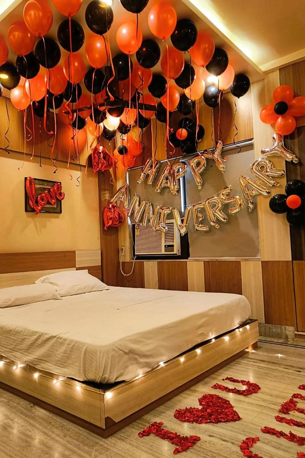 Red and black anniversary decoration at home with ceiling balloons, Happy Anniversary foil letters and LOVE wall decor
