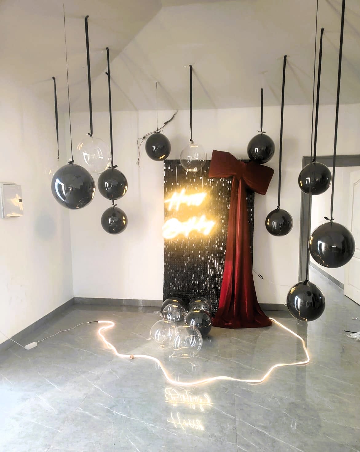 Simple black balloon birthday decoration with shimmer backdrop and warm lights