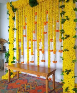 Alternative yellow floral backdrop with green foliage and orange-and-white hanging accents behind a wooden table