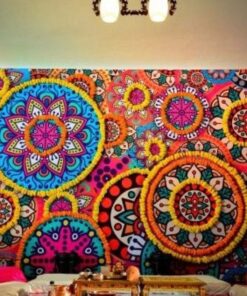 Wide colourful mandala backdrop outlined with yellow and orange garlands behind ceremonial seating and floor styling