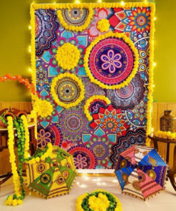 Illuminated mandala backdrop with yellow garlands, two Rajasthani umbrellas and a selfie hoop beside wooden tables