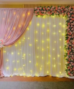 Alternative pink and white draped backdrop with a pink floral border and warm fairy lights