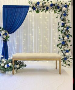 Alternative blue and white draped backdrop with a floral border, fairy lights and an upholstered bench