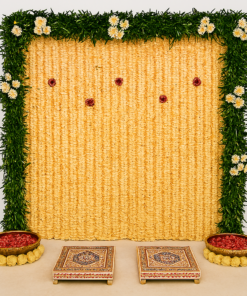 Alternative cream-coloured floral puja backdrop with a green foliage border, two decorated chowkis and flower-filled bowls